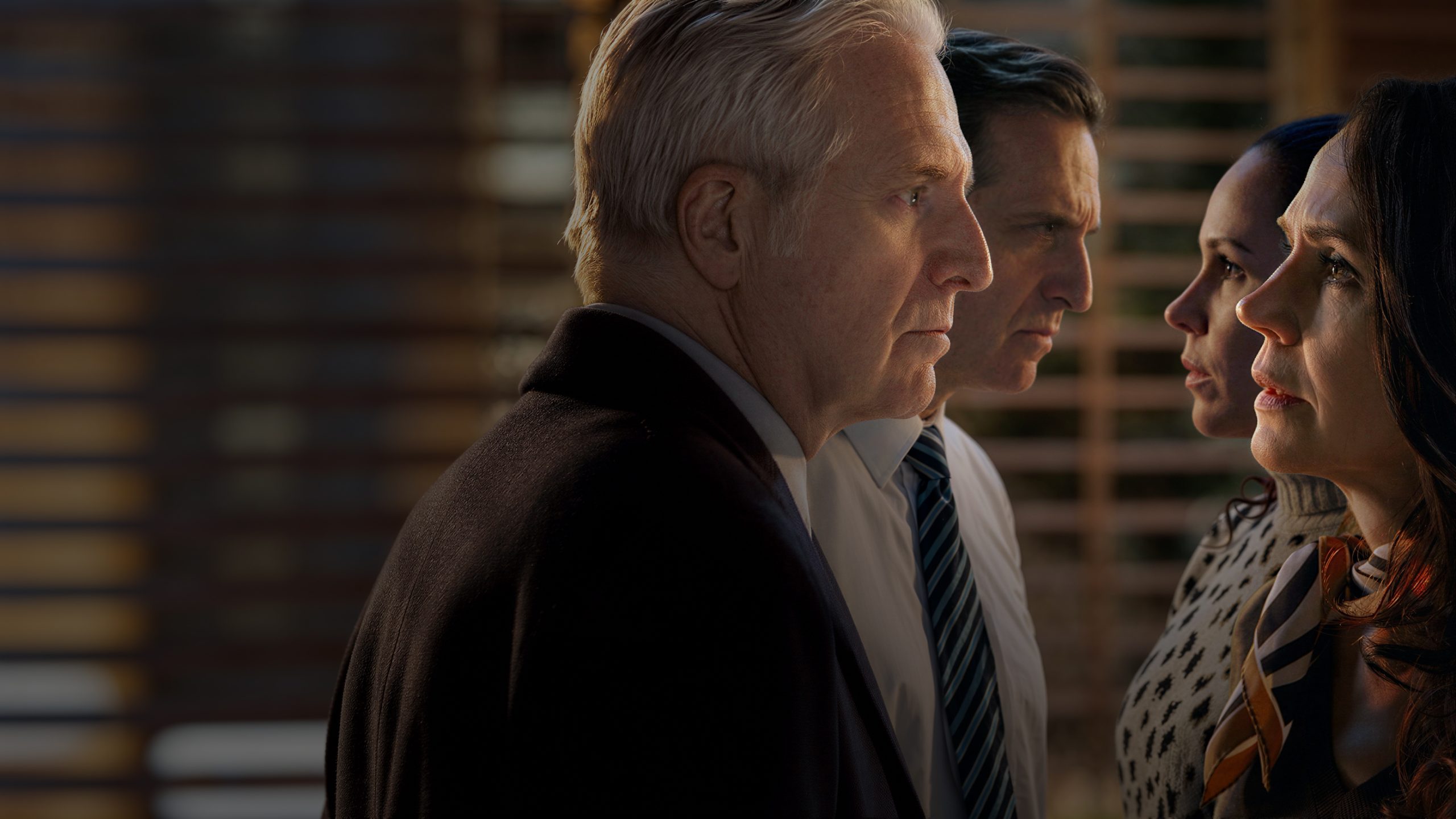 Trois personnages d'Un Si Grand Soleil (2 hommes et 2 femmes) qui se regardent dans les yeux face à face, avec en bas le logo Un Si Grand Soleil. Les hommes ont l'air menaçants, les femmes stupéfaites. La scène se passe dans un bureau plutôt sombre.